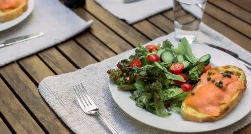 Piatto con insalata e crostino al salmone su un tavolo in legno
